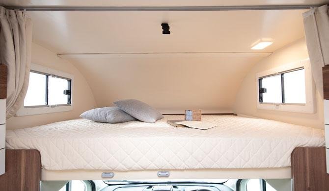 Het bed boven de bestuurderscabine in de Just Go Rambler camper