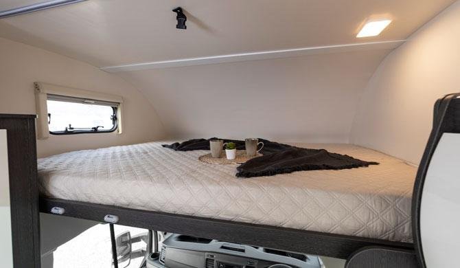 Het bed boven de bestuurderscabine in de Just Go Adventurer camper